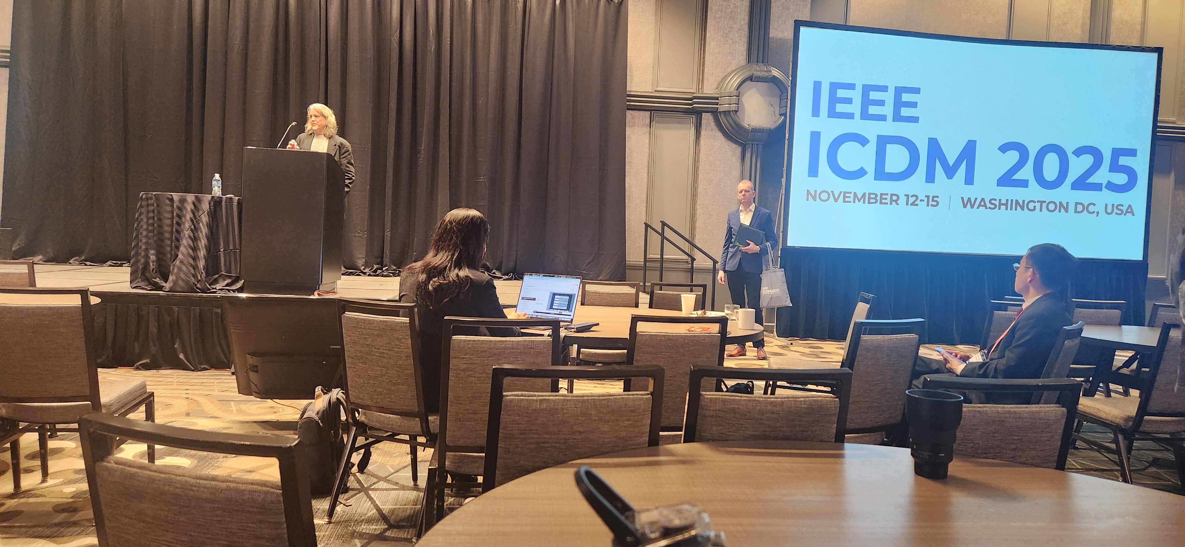 Keynote speaker on stage with ICDM 2025 screen