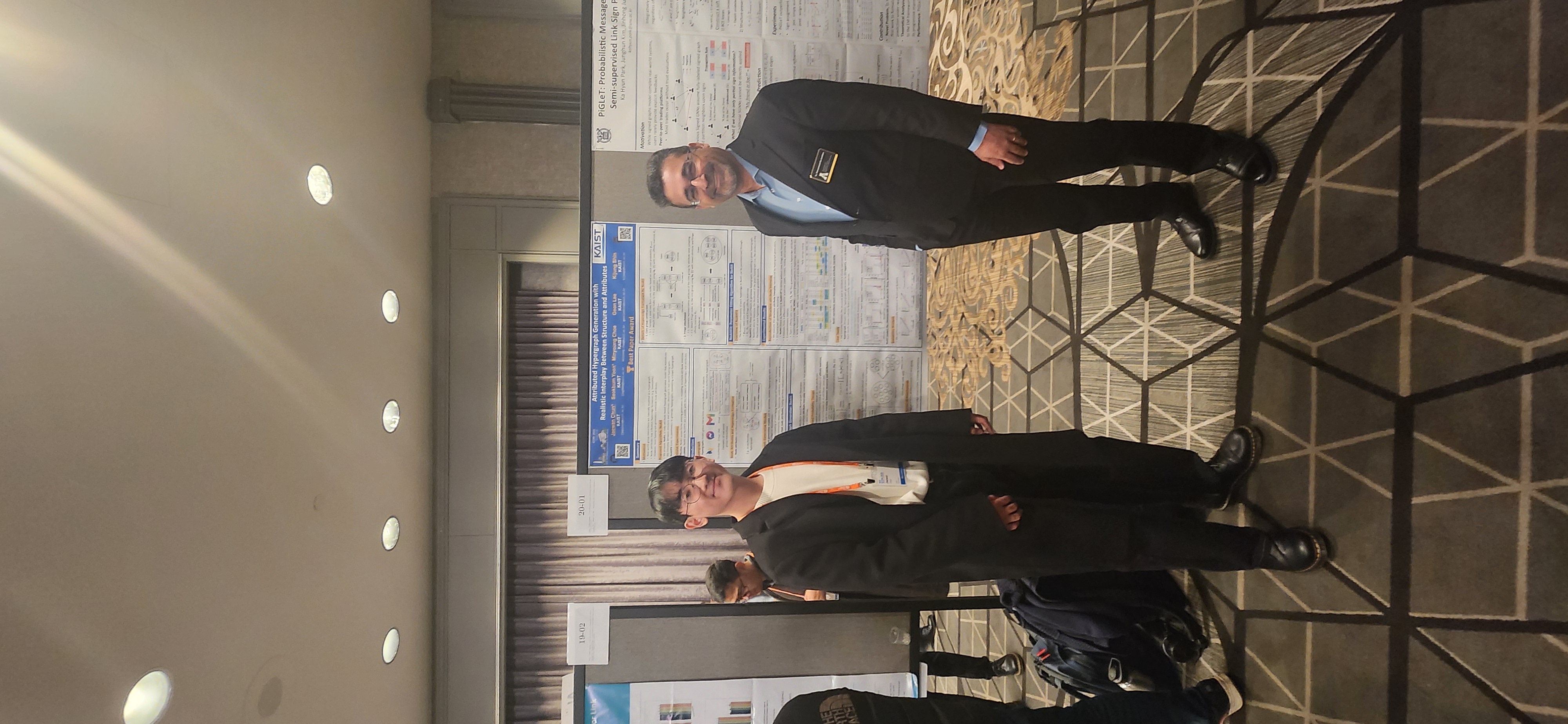 Two researchers standing in front of a best paper award poster.